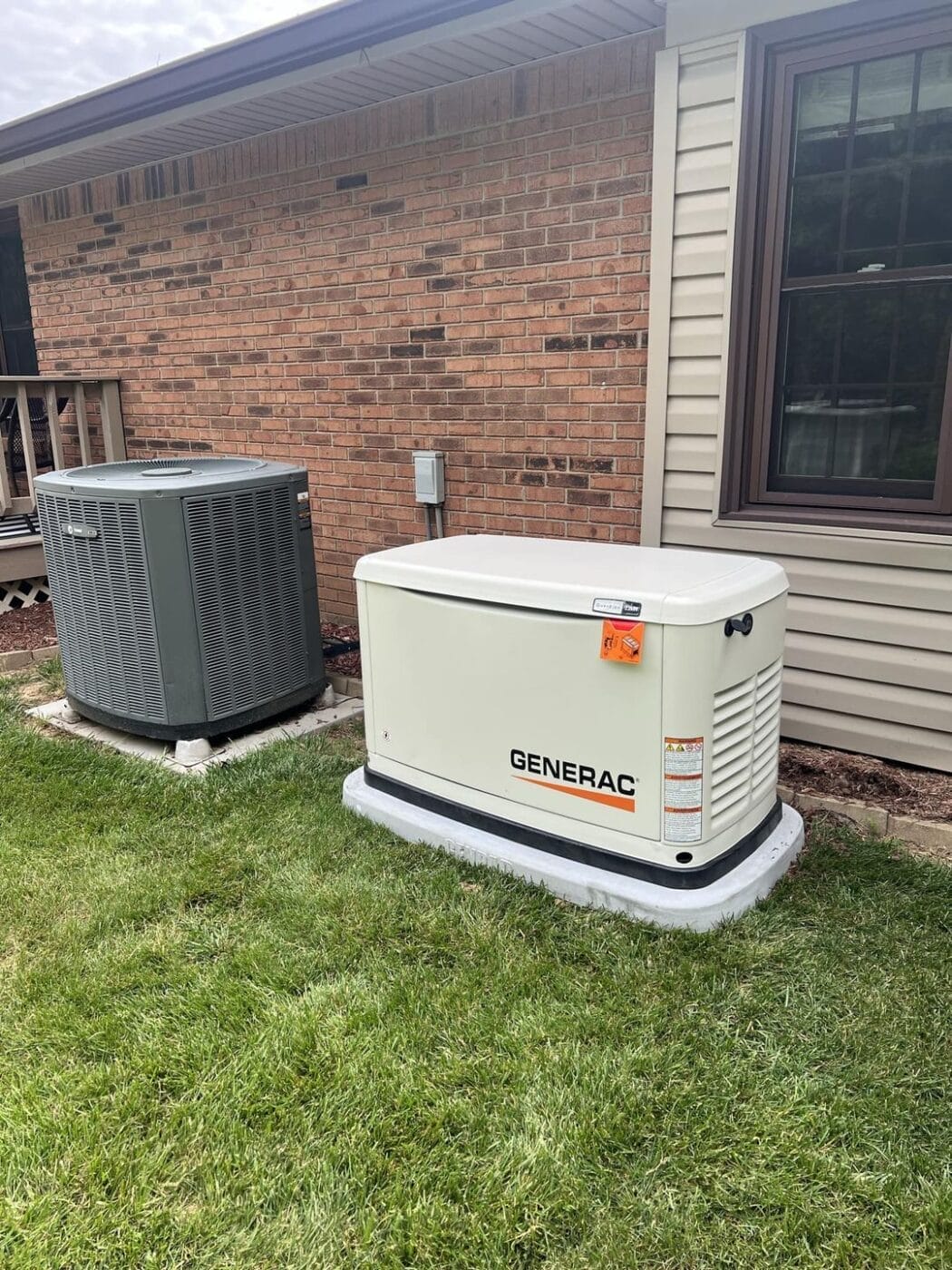 Finished Generac whole-home standby generator installed beside a brick house
